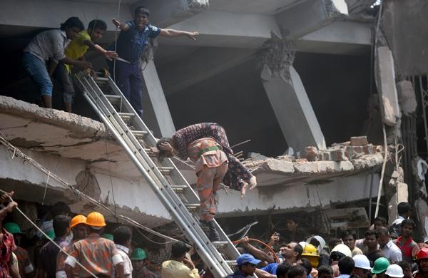 Bombeiro resgata vítima em meio a escombros de prédio que desabou em Bangladesh (France Press)