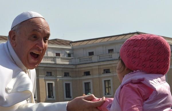 O papa Francisco brinca com uma criança no Vaticano (France Presse)