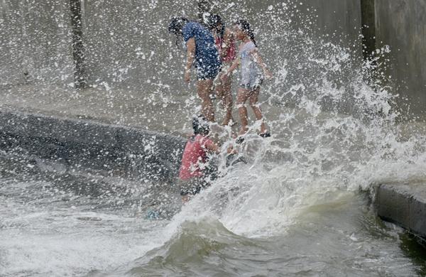 Crianças ignoram o perigo e brincam em ondas durante tempestade nas Filipinas (France Press)