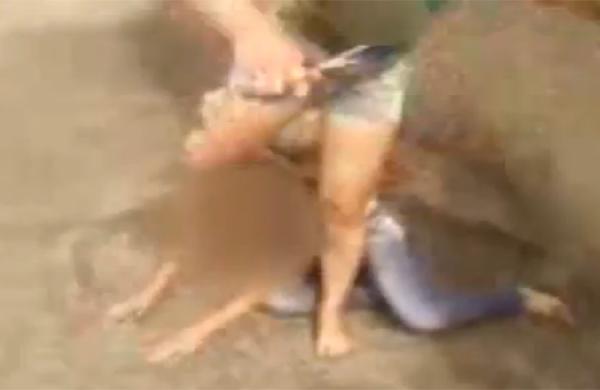 Agressora segura a tesoura em uma das mãos e o chumaço de cabelo da vítima na outra (Captura de vídeo)