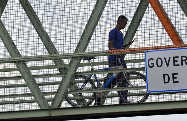 Homem passa com sua bicicleta em passarela (Dominique Torquato/AAN)