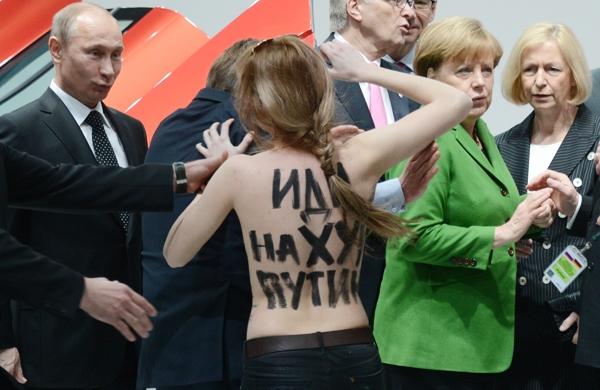 Vladimir Putin (E) e Angela Merkel (D) são surpreendidos por manifestante de topless (France Press)