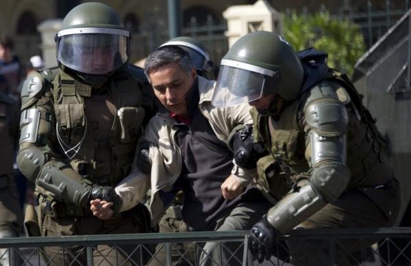 Policiais chilenos seguram rapaz em primeiro protesto estudantil do ano em Santiago (France Press)
