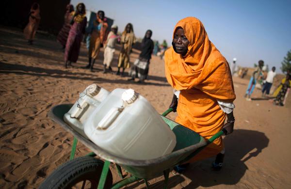 Mulher sudanesa de Jebel Saiey no norte de Darfur, transportando galões de plástico cheios de água em um carrinho de mão no campo de Abu Shouk (France Press)