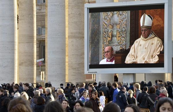 Fieis acompanham primeira missa de papa Francisco transmitida em um telão no Vaticano (France Press)