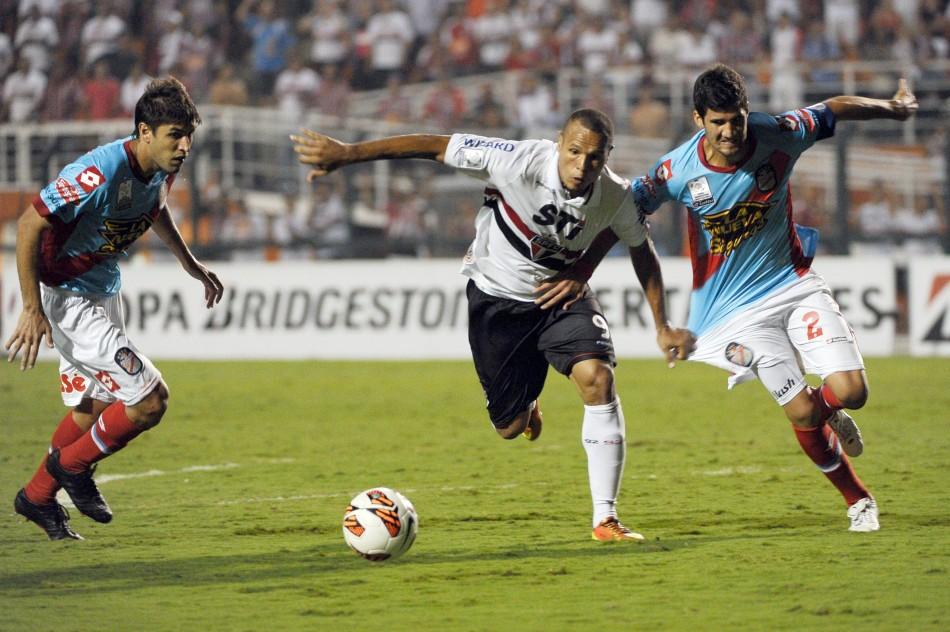 Luis Fabiano tenta passar por dois marcadores do Arsenal de Sarandi: atacante do São Paulo foi expulso após o encerramento do jogo por reclamar com o árbitro (Yasuyoshi Chiba/France Press)