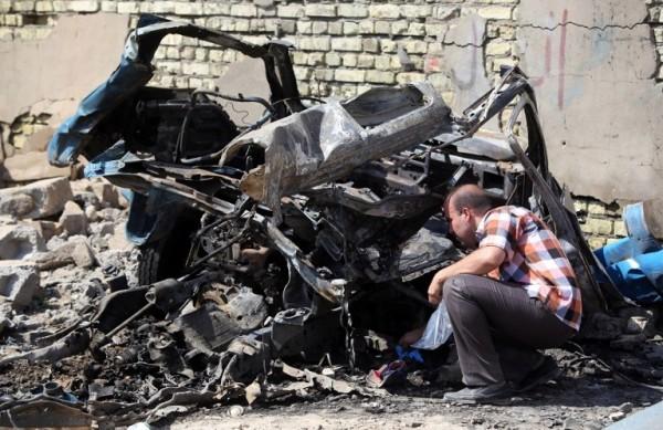 Homem observa veículo carbonizado após explosão de carro-bomba, no Iraque (France Press)