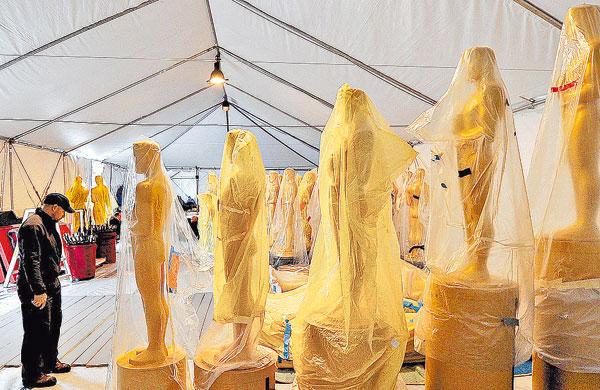 Estátuas que representam o Oscar cobertas com plástico em tenda em frente ao Dolby Theatre, onde será realizada a premiação  (AFP)
