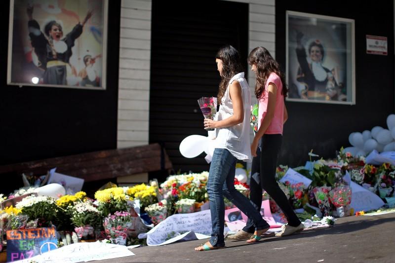 Jovens levam flores para depositá-las em frente à boate Kiss (France Press)