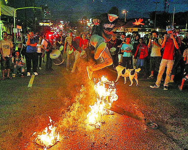 Manifestante pula catraca incendiada durante protesto por melhorias do transporte público realizado por moradores da região do Grajaú, em SP ( Cedoc/RAC)