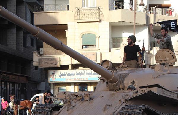 Membro do grupo militante IS (estado isl&acirc;mico) desfila com um tanque em uma rua na cidade S&iacute;ria  (AFP)