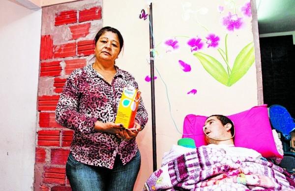 Maria Aparecida mostra o &uacute;ltimo litro de alimento enteral para o filho Denis ( Rodrigo Zanotto/ Especial para a AAN)