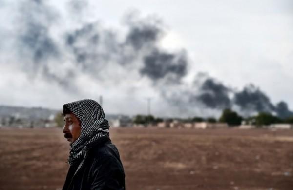 Homem curdo est&aacute; pr&oacute;ximo &agrave; fronteira entre Turquia e S&iacute;ria, de onde se v&ecirc; fuma&ccedil;as do combate em de Kobane (France Press)