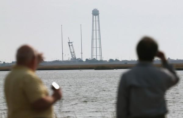 Um dia ap&oacute;s a explos&atilde;o do Antares, dois homens olham a plataforma de onde foi lan&ccedil;ado o foguete, na Virg&iacute;nia (leste dos EUA) (France Press)