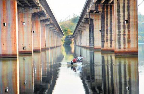 Homens passam de barco pela Represa Atibainha, sob a Rodovia D. Pedro I, uma das que comp&otilde;e o Cantareira em Nazar&eacute; Paulista; imagem de fevereiro deste ano ( Cedoc/ RAC)