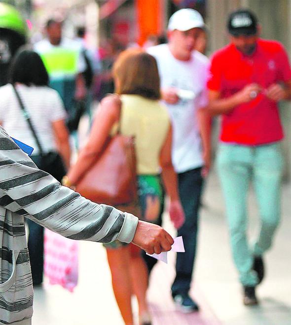 Panfleteira tenta entregar folheto, mas é ignorada por pedestre que seguiu o seu caminho na Rua 13 de Maio: muitos pegam, mas se "livram" depois (Leandro Ferreira)