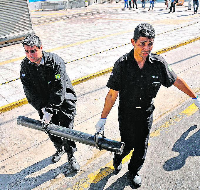 Seguranças a recolhem aríete que foi usado pelos criminosos para arrombar portas da agência bancária atacada (Christiano Diehl Neto/Gazeta de Piracicaba)