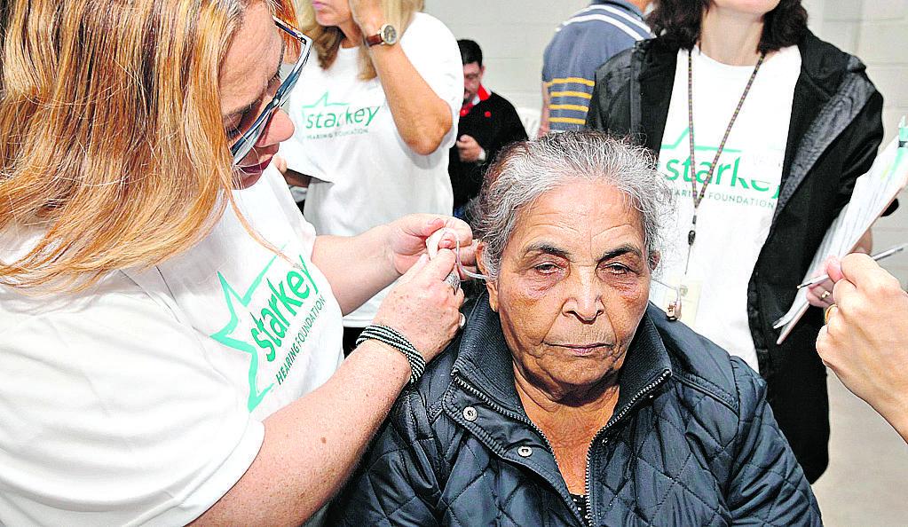 Técnica coloca o aparelho em paciente: parceria com a empresa Starkey Hearing Foundation (Divulgação)