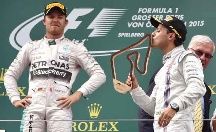 O piloto alem&atilde;o Nico Rosberg, que venceu o GP da &Aacute;ustria, observa o brasileiro Felipe Massa beijar o trof&eacute;u de 3&ordm; colocado (France Press)
