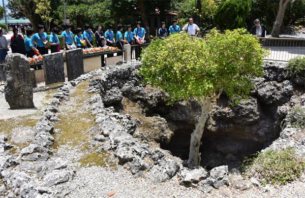 Estudantes japoneses observam uma cratera que serviu como hospital de campo durante a batalha de Okinawa (France Press)