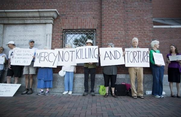 Manifestantes a favor da pena de morte seguram cartazes em frente ao tribunal em que ocorria o julgamento de Djokhar Tsarnaev, co-autor do atentado durante  maratona de Boston (France Press)
