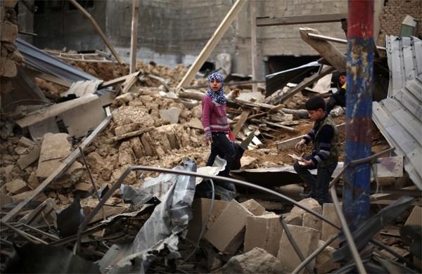 Crian&ccedil;as s&iacute;rias andam por escombros ap&oacute;s bombardeio do regime de Bashar Al-Assad (France Press)