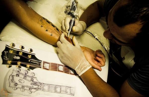 Beto Martinelli tatua uma guitarra Gibson em um m&uacute;sico  (Osvaldo Furiatto)