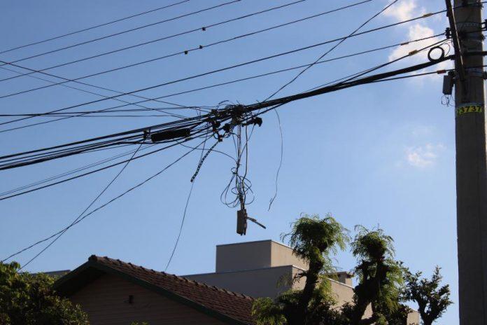 O emaranhado de fios e cabos de telefonia soltos e abandonados nos postes de energia elétrica coloca em risco a segurança das pessoas nas ruas (Divulgação)