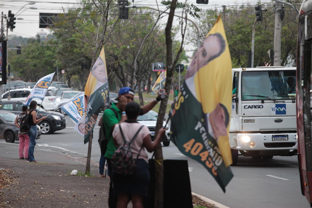 Cabos eleitorais agitam bandeiras de candidatos na avenida Dr. Theodureto de Almeida Camargo: movimentação deve aumentar na reta final (Rodrigo Zanotto)