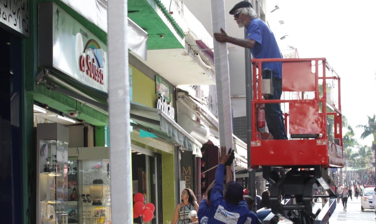 Operários instalam estruturas que darão sustentação à cobertura de guarda-chuvas coloridos na Rua 13 (Rodrigo Zanotto)