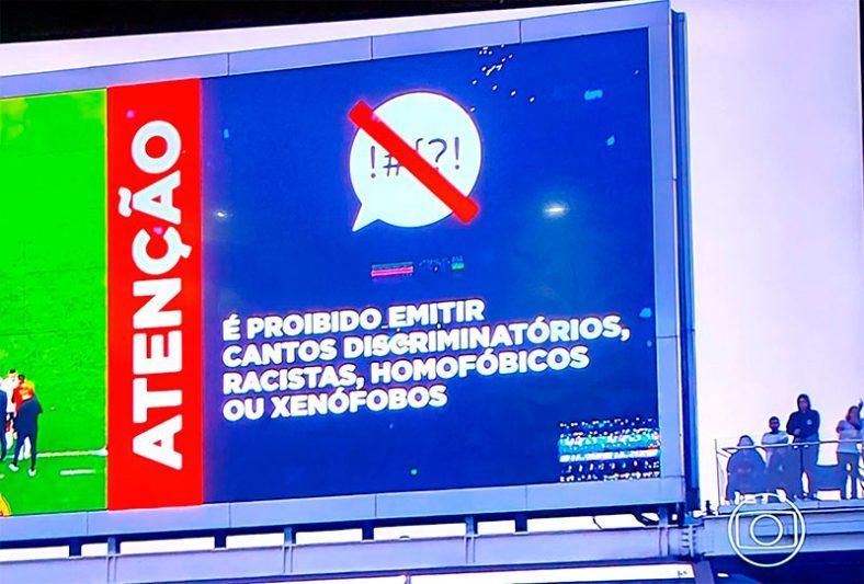 No telão da Neo Química Arena, um aviso pedia para que a ação dos torcedores fosse interrompida. "É proibido emitir cantos discriminatórios, racistas, homofóbicos ou xenófobos" dizia a mensagem. (Reprodução/TV Globo)