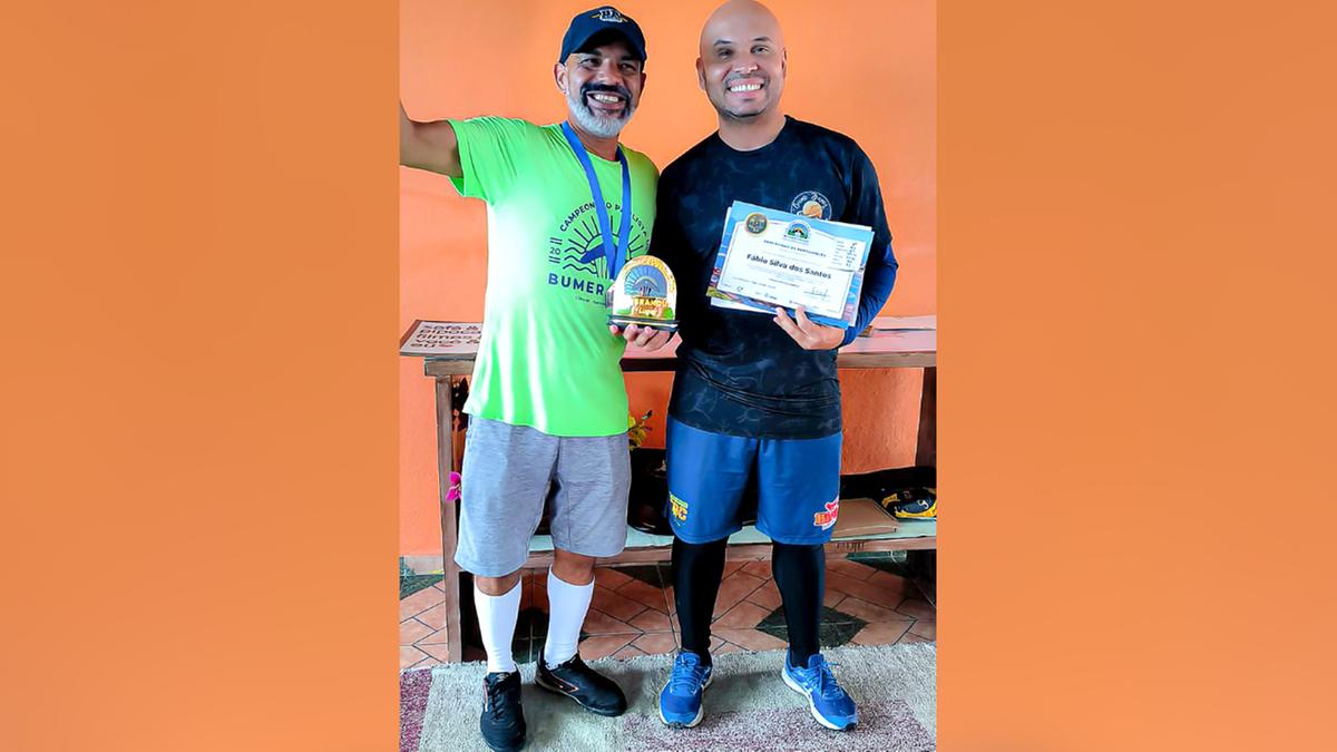 Fábio Santos (à direita) exibe o troféu e certificado de campeão (Divulgação)
