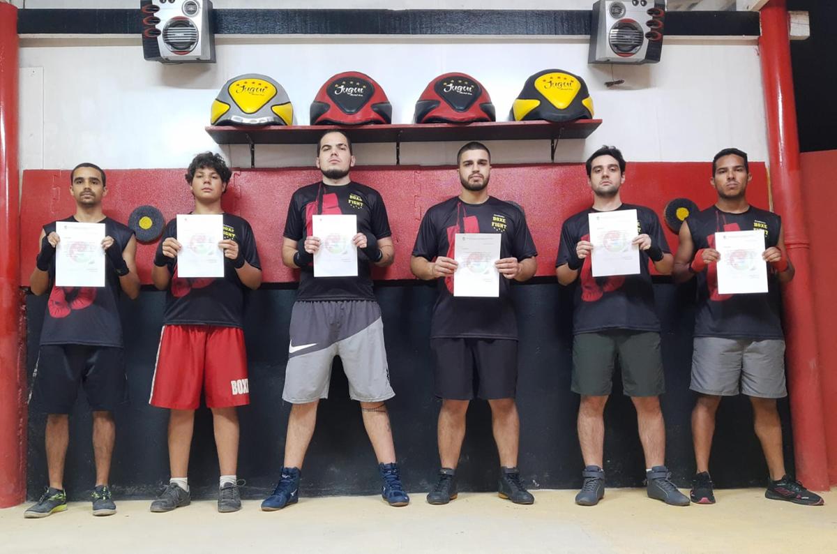Lutadores exibem o comunicado de convocação emitido pela Organização Internacional de Artes Marciais e Esportes de Contato para o evento na Argentina (Divulgação)