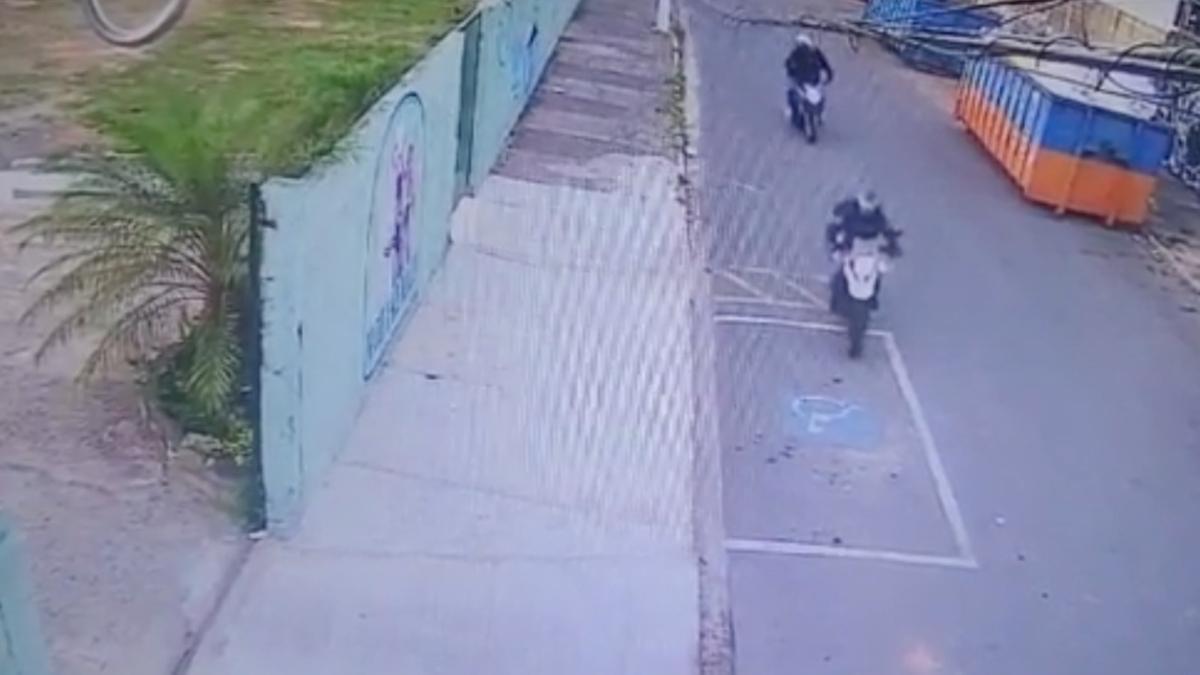 Imagens mostram o professor chegando de moto para trabalhar, por volta das 6h da manhã. Ele passava pelo portão da escola quando um outro motociclista se aproximou e o garupa atirou contra ele. Em seguida, os criminosos fugiram (Reprodução)