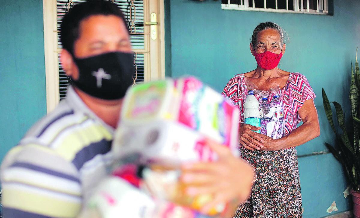 Feliz da vida, Maria da Penha Rodrigues, 60 anos, ao fundo, recebe doações de alimentos e produtos de higiene na Garagem do Bem, ação solidária criada por duas amigas de Sumaré (Diogo Zacarias/ Correio Popular)