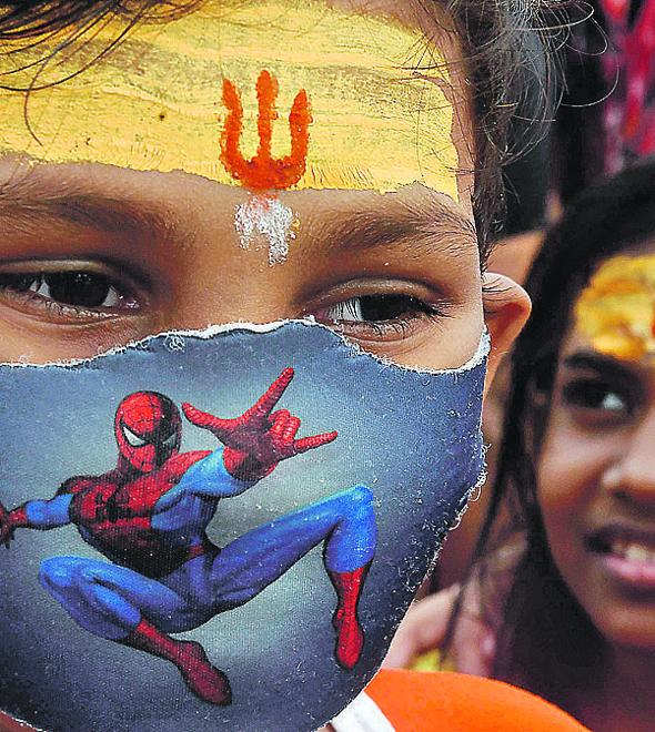 Jovem devoto do deus Shiva com máscara improvisada em Delhi, capital da Índia, que ultrapassou 50 mil mortes (Dibyangshu Sarkar/AFP)
