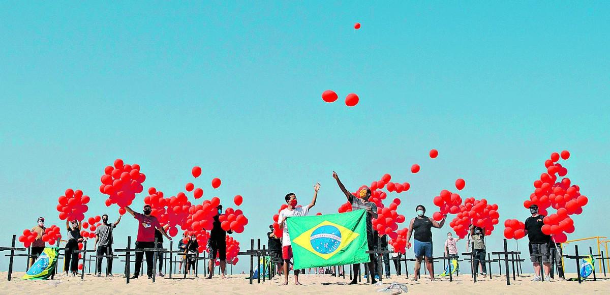 Cruzes e balões vermelhos na praia de Copacabana, no Rio, lembram da triste marca alcançada pelo País na pandemia (Mauro Pimentel/AFP)