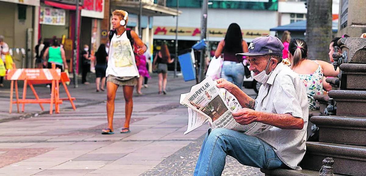 Leitor do Correio Popular mantém-se concentrado nas notícias, enquanto descansa diante da Catedral (Adriano Rosa/Especial para a AAN)