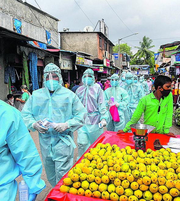Agentes de saúde caminham em feira livre na capital da Índia: projeção de 500 mil casos na cidade (Indranil Mukherjee/AFP)