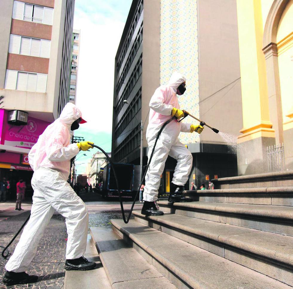 Homens aplicam produto que combate a proliferação do coronavírus, micro-organismo causador da covid-19  (Diogo Zacarias/ Correio Popular)
