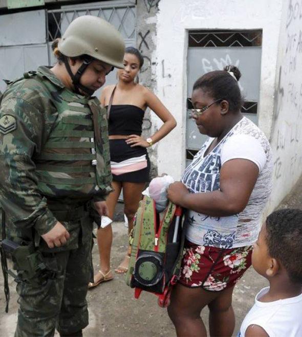 Uma militar revista mochila de menino durante operação na Favela Kelson's (Domingos Peixoto/O Globo)