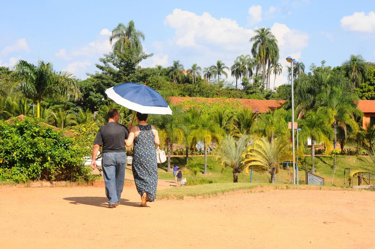 Casal usa guarda-chuva contra o sol durante passeio no Pq. das Águas (Elcio Alves/ AAN)