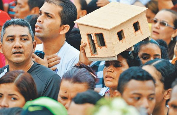 Fiel carrega miniatura de uma casa, enquanto dezenas de pessoas conduzem uma corda, tradição iniciada no século 19 e que se tornou um dos símbolos da festividade ao longor
dos anos (Marcello Casal/ Agência Brasil)
