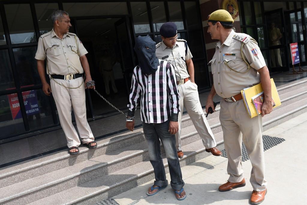Ravinder Kumar foi conduzido com a cabe&ccedil;a coberta por um capuz e escoltado por dois policiais (Sajjad Hussain/France Press)