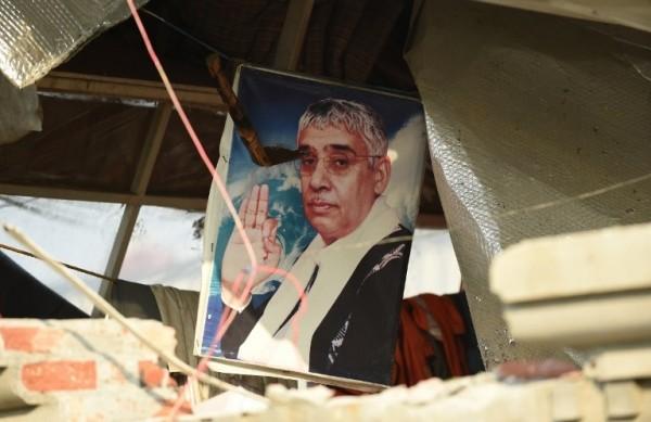 Foto de Rampal Maharaj nos escombros do que seria a entrada de seu monast&eacute;rio, destru&iacute;da pelos policiais que o capturaram (France Press)