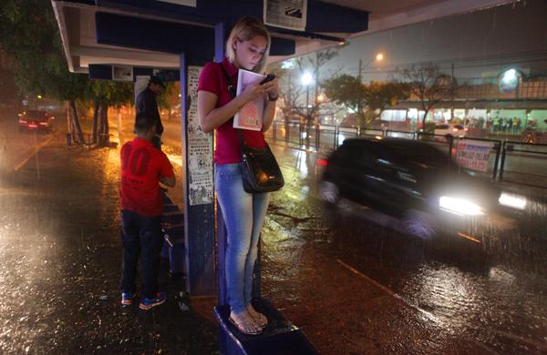 Jovem se refugia da chuva em ponto de &ocirc;nibus na Avenida John Boyd Dunlop ontem &agrave; noite: v&aacute;rios bairros ficaram sem energia el&eacute;trica ( Rodrigo Zanotto/ Especial para a AAN)