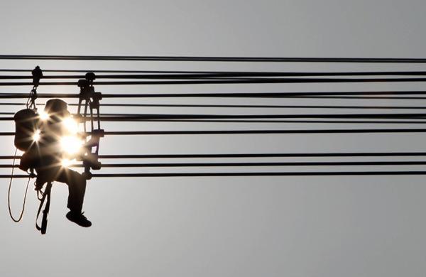 Oper&aacute;rios de empresa de energia el&eacute;trica trabalham sobre fio de alta tens&atilde;o  (AFP)