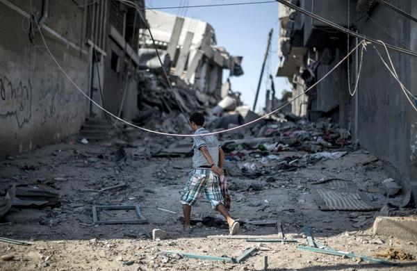 Garoto palestina caminha sobre escombros de edif&iacute;cio bombardeado por Israel na Faixa de Gaza (France Press)