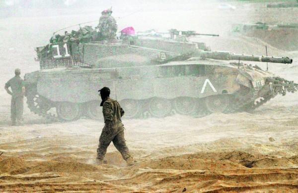 Soldado israelense passa por um tanque na fronteira entre Israel e a Faixa de Gaza, controlada pelo Hamas (AFP)