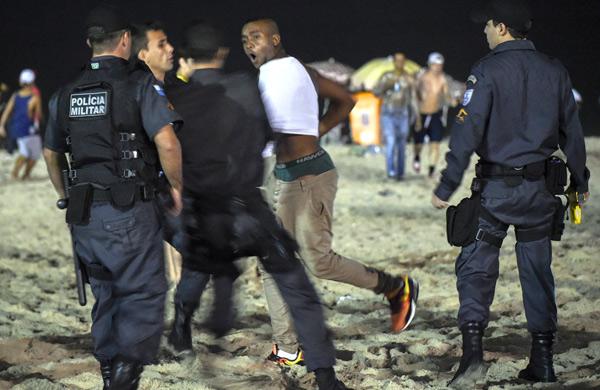 Homem &eacute; detido pela pol&iacute;cia enquanto assiste &agrave; semifinal da Copa entre Brasil e Alemanha em tela p&uacute;blica nas ruas do Rio de Janeiro (AFP PHOTO / YASUYOSHI CHIBA)